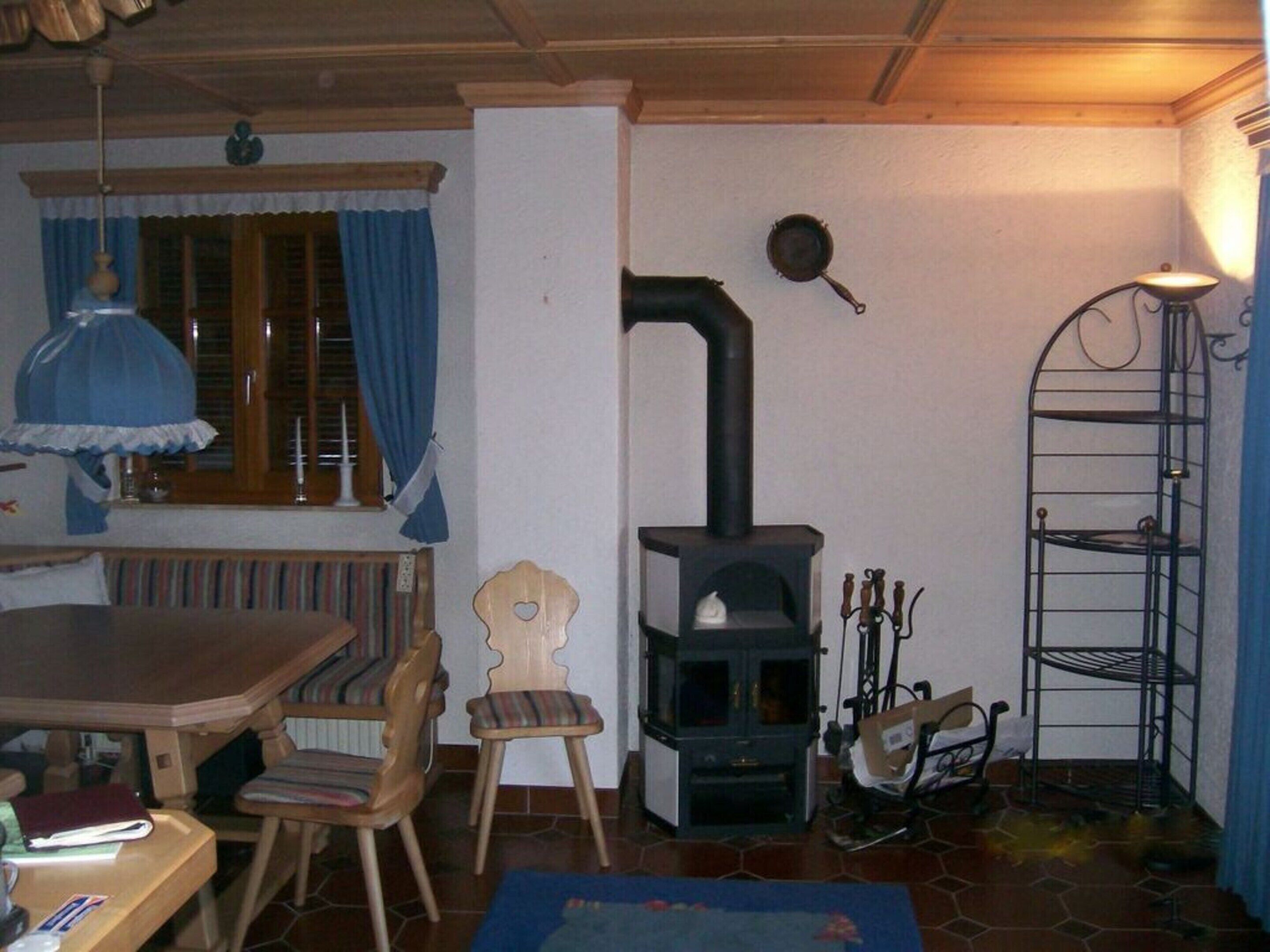 A cozy living room with a wooden table, chairs, a sofa, a fireplace, and a lamp.