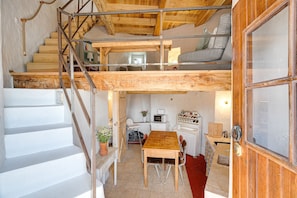 A multi-level wooden interior with a staircase, a dining area, and a kitchen. - Ericeira Windmill by Hopstays | Wild Refuge (Mafra)