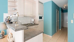 Une cuisine moderne avec des meubles de couleur bois clair, un plan de travail en granit, un four à micro-ondes encastré et une machine à café.