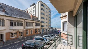 Une vue de rue avec des voitures garées, un immeuble doté de nombreuses fenêtres et un ciel dégagé.