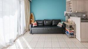 Un salon moderne avec un mur d’accent de couleur turquoise, un canapé en cuir noir et une planche de surf en bois.