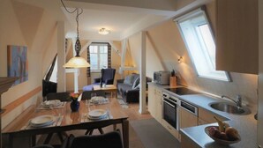 A compact kitchen with a dining area, a small seating space, and a window providing natural light. - Villa Balticum Modern Retreat (Zingst)