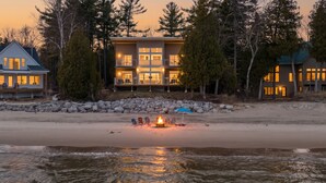A beachfront property with a large building, a fire pit, and a sandy beach. - Modern | Beachfront | Sleeps 10 (Oostburg)