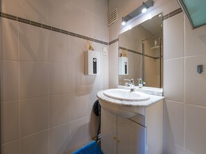 Une salle de bain avec un lavabo blanc, un miroir et un tapis de bain bleu.