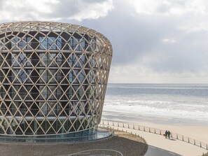 Un bâtiment moderne à la façade géométrique, situé près d’une plage.