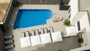 A rooftop pool with a blue pool, white lounge chairs, and umbrellas. - Belvilla by OYO Apartamento con Patio (Fuengirola)