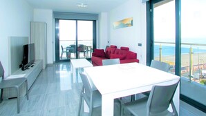 A modern living room with a TV, a dining table, and a red sofa. - Belvilla by OYO Apartamento con Patio (Fuengirola)