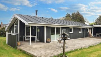 A modern house with a covered patio, a chimney, and a deck.