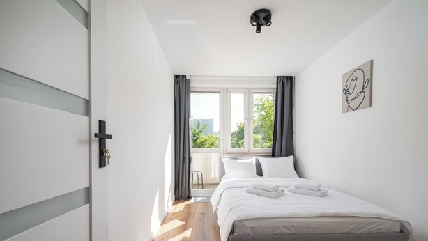 A bedroom with a bed, a window, and a door. - Ochota Comfort Apartment (Warszawa)