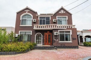 Un edificio de dos plantas con una entrada central, un balcón y varias ventanas.