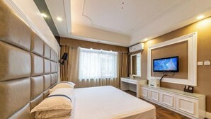 A hotel room with a large bed, a TV, a desk, and a mirror.