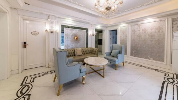 A luxurious living room with a tufted sofa, a round coffee table, and a chandelier.