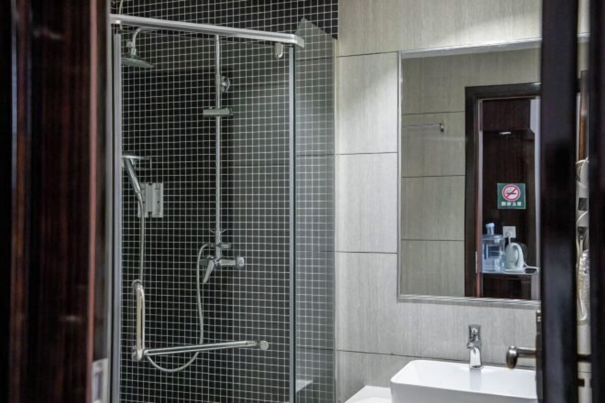 Un baño moderno con ducha de vidrio, un lavamanos blanco y un espejo encima.