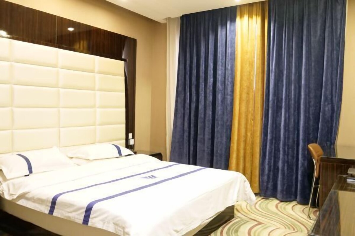Una habitación de hotel con una cama grande, cabecera, un escritorio y una silla.