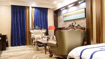 A hotel room with a large bed, a chaise lounge, a small table, and a lamp.