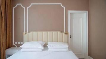 A hotel room with a bed, a nightstand, a door, and a wall with a decorative molding.