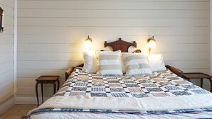 A bedroom with a wooden headboard, a quilted bedspread, two bedside tables, and wall-mounted lamps. - 6 Person Holiday Home in Hedekas-by Traum (Hedekas)