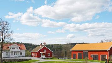 Ett lantligt landskap med ett vitt hus, en röd lada och en byggnad med ett gult tak.