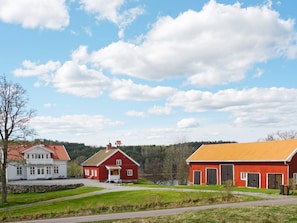 Paisaje rural con una casa blanca, un granero rojo y un edificio de techo amarillo.