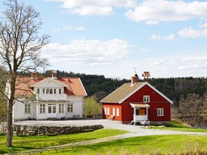 Une maison blanche avec un toit rouge et une grange rouge dotée d’un porche blanc.