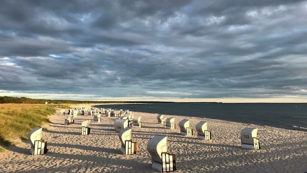 Una spiaggia con file di sedie bianche e diversi tende bianche.
