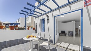 A patio with a table and chairs, potted plants, and a blue-framed pergola. - "Oasis" Apartment in Playa Blanca | Lanzarote - Spain (Playa Blanca)