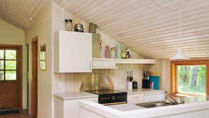 A kitchen with white cabinetry, a stove, and a window with a view of trees. - 6 Person Holiday Home in Nykobing Sj (Nykobing Sjaelland)