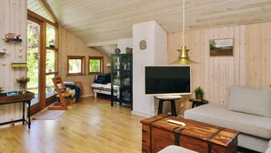 A spacious living room with wooden walls and floors, a sofa, a television, and a cabinet. - 6 Person Holiday Home in Nykobing Sj (Nykobing Sjaelland)