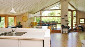 A spacious kitchen with a large island, wooden flooring, and a high ceiling with exposed beams. - 6 Person Holiday Home in Nykobing Sj (Nykobing Sjaelland)
