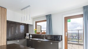 Une cuisine moderne dotée d’un plan de travail en marbre, d’appareils électroménagers intégrés et offrant une vue sur la campagne grâce à une grande fenêtre.