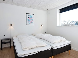Ein Schlafzimmer mit zwei Betten, einem Nachttisch und einem gerahmten Bild an der Wand.