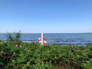 A lifebuoy on a pole by the sea, with waves and a clear sky. - 4 Star Holiday Home in Borkop (Borkop)
