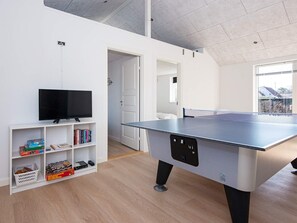 A room with a ping pong table, a television on a shelf, and a door leading to another room. - 4 Star Holiday Home in Borkop (Borkop)