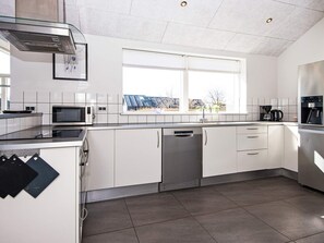 Eine moderne Küche mit weißen Schränken, einem eingebauten Geschirrspüler, einer Mikrowelle und einer Kaffeemaschine.