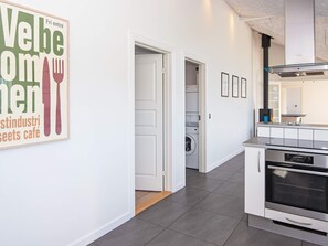 A modern kitchen with a built-in oven and a dining area with a wall-mounted picture. - 4 Star Holiday Home in Borkop (Borkop)