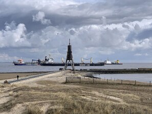 A coastal scene with a large ship named 'Wisdom Line' docked at a pier. - Nice Apartment Near Beach (Cuxhaven)