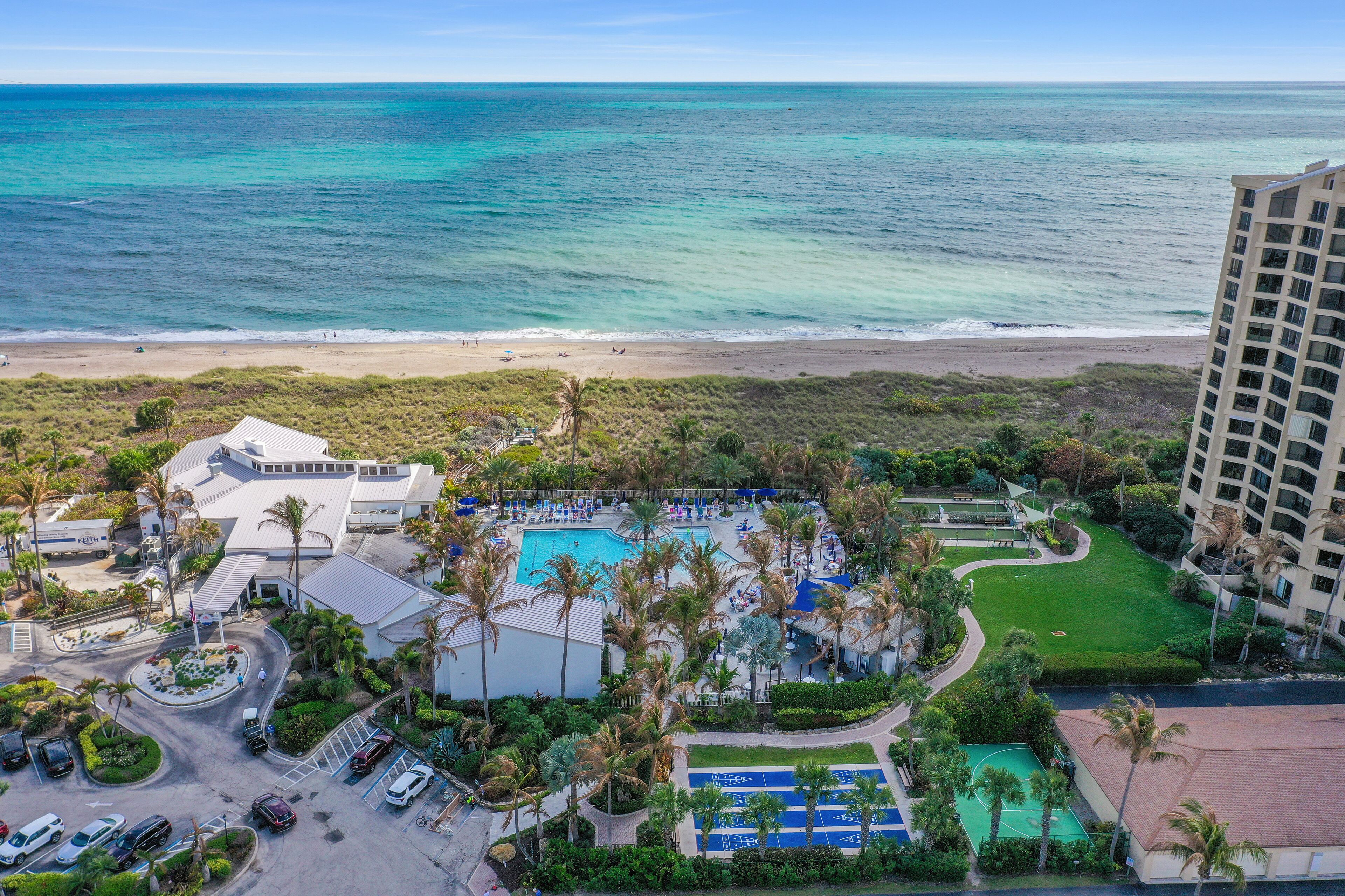 A resort with a pool, palm trees, and a beach view.