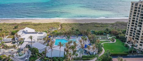 A resort with a pool, palm trees, and a beach view.