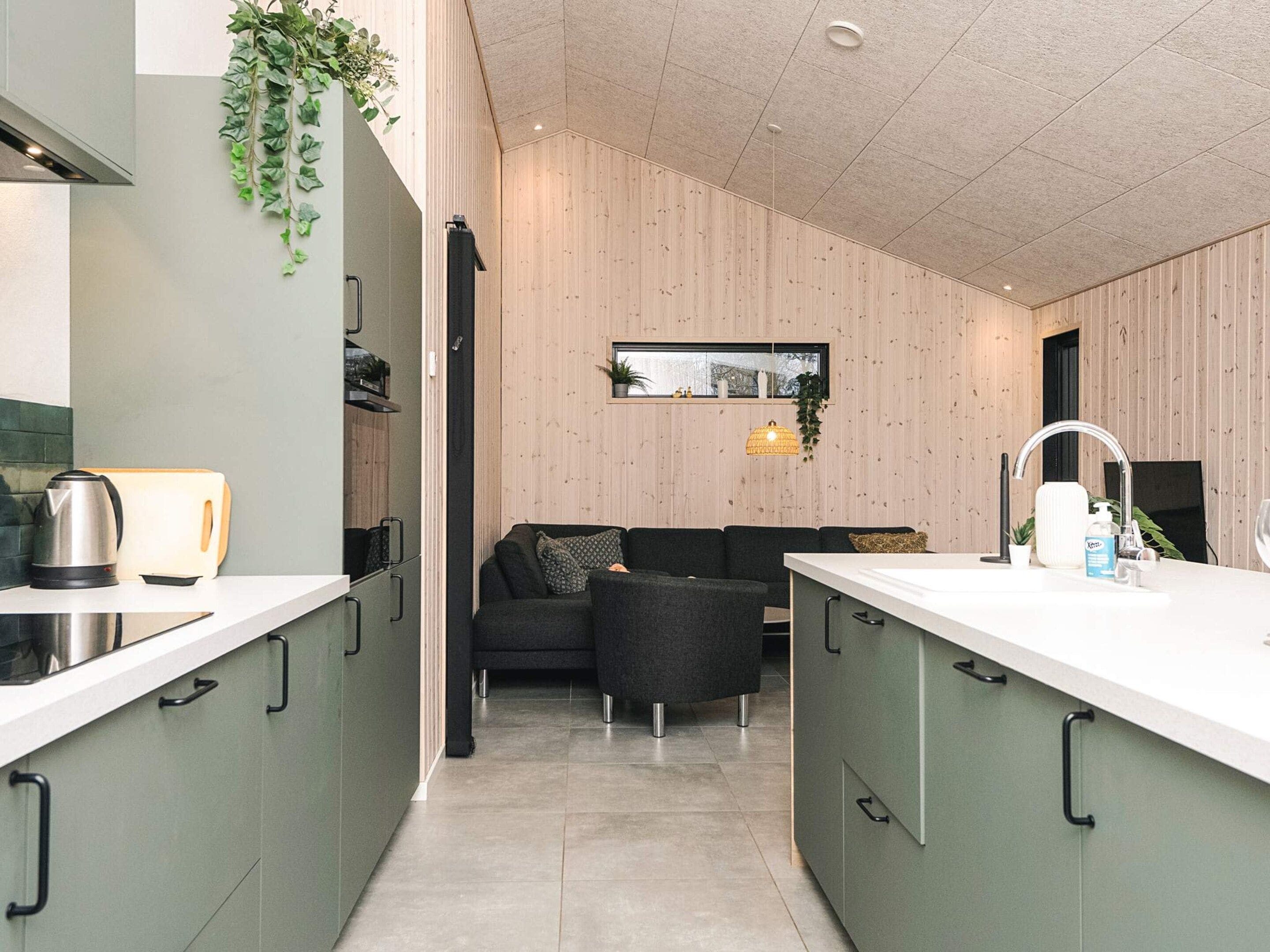 Une cuisine moderne dotée d’un îlot central, de meubles de rangement intégrés et d’un coin salon avec un canapé et des fauteuils.