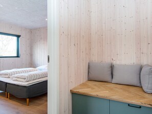 A room with a bed, a bench with cushions, and a window.