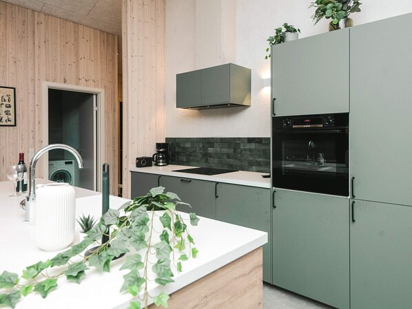 A modern kitchen with a built-in oven, a coffee maker, and a sink.