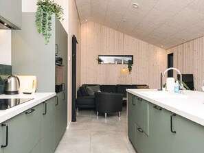 A modern kitchen with a central island, a built-in oven, and a dining area with a sofa and table.