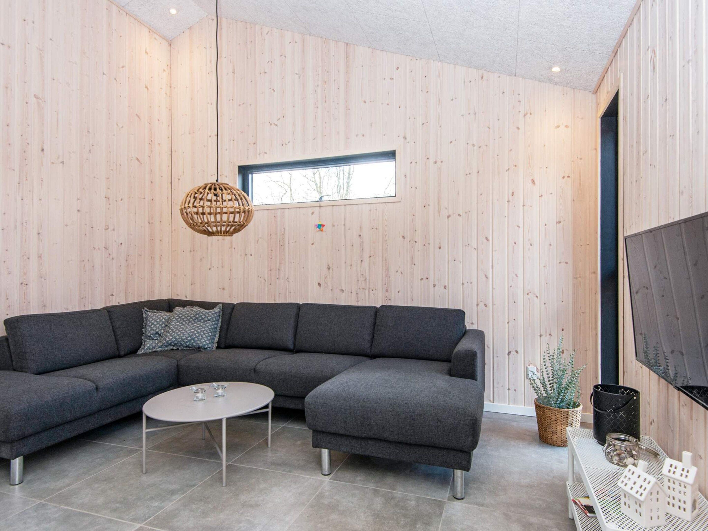 A modern living room with a sectional sofa, a round coffee table, and a large window.