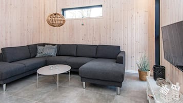 A modern living room with a sectional sofa, a round coffee table, and a large window.