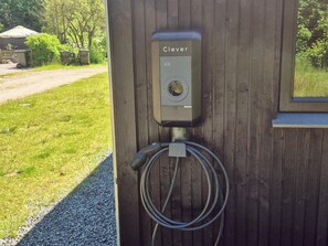 A Clever electric vehicle charging station mounted on a wooden wall with a hose attached.