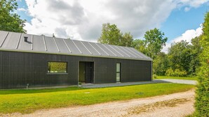 Un bâtiment moderne avec un toit en métal, une petite fenêtre et une porte.
