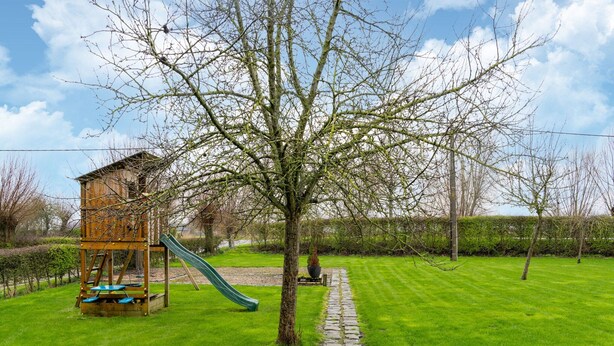A playground with a slide and climbing structure, surrounded by a well-maintained lawn and a stone pathway. - Comfortable Home for a Group With a Large Garden (Diksmuide)