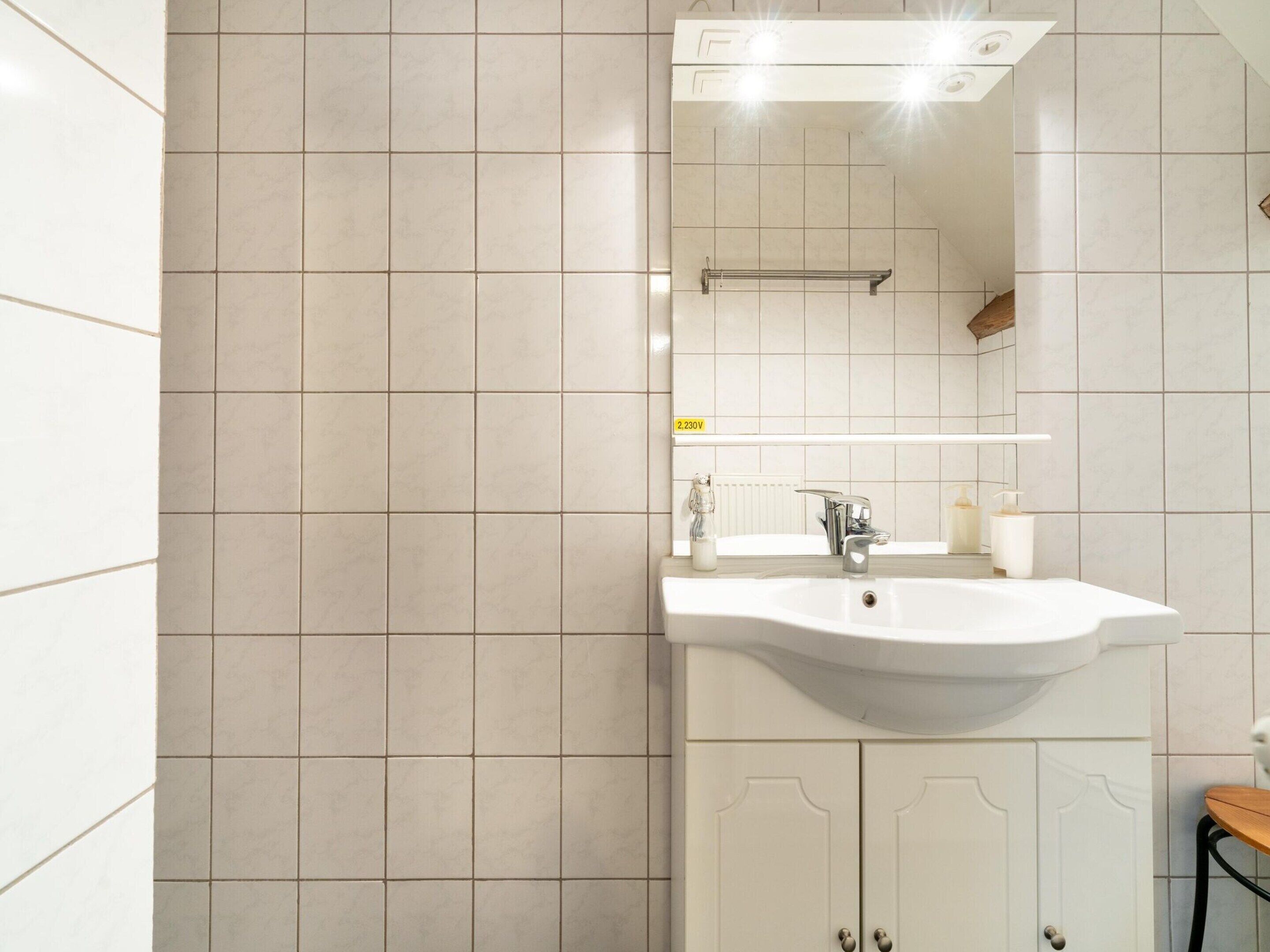 A modern bathroom with a white sink, a mirror, and a towel rack.