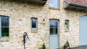 A stone building with a green door, two windows, and a small lamp. - Comfortable Home for a Group With a Large Garden (Diksmuide)