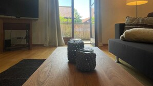 A living room with a television, a sofa, a lamp, and a wooden table with jars. - Holiday Apartment Lucky guy (Oberstaufen)